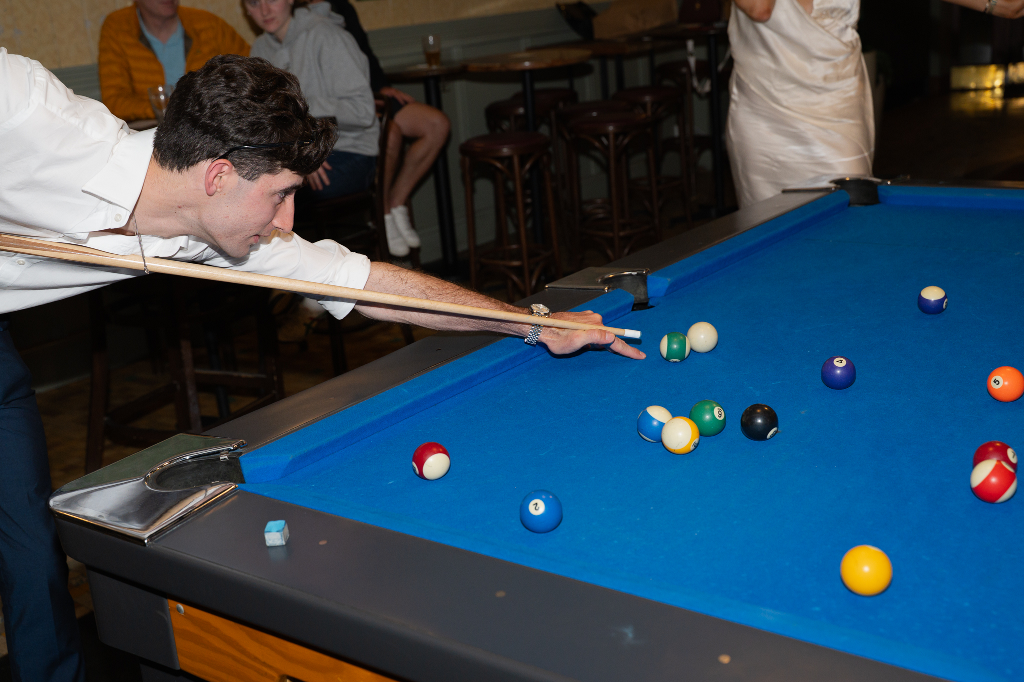 Man aiming his cue while playing pool, focusing on his next shot on the billiard table.